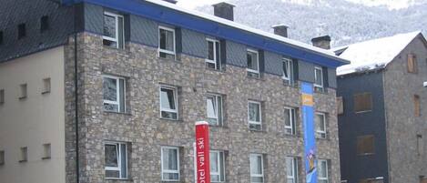 Un hotel de varios pisos con fachada de piedra y numerosas ventanas.