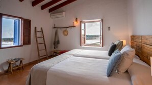 Une chambre avec deux lits, une échelle en bois, une petite table et une vue sur une rivière.