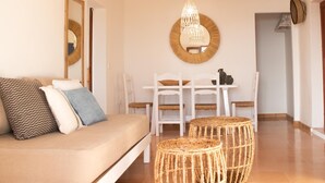 Un salon chaleureux avec un canapé, une table à manger et des chaises, ainsi qu’un luminaire suspendu.