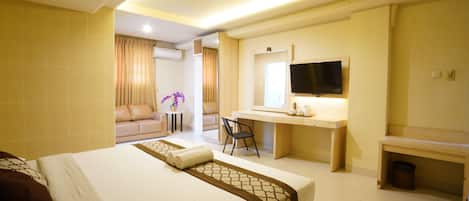 A hotel room with a large bed, a desk with a chair, a television, and a small table.