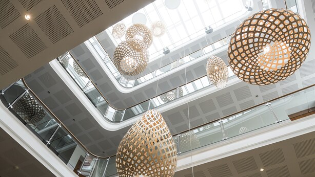 Un atrium à plusieurs niveaux, doté de plafonds aux motifs géométriques modernes et de luminaires sphériques suspendus.