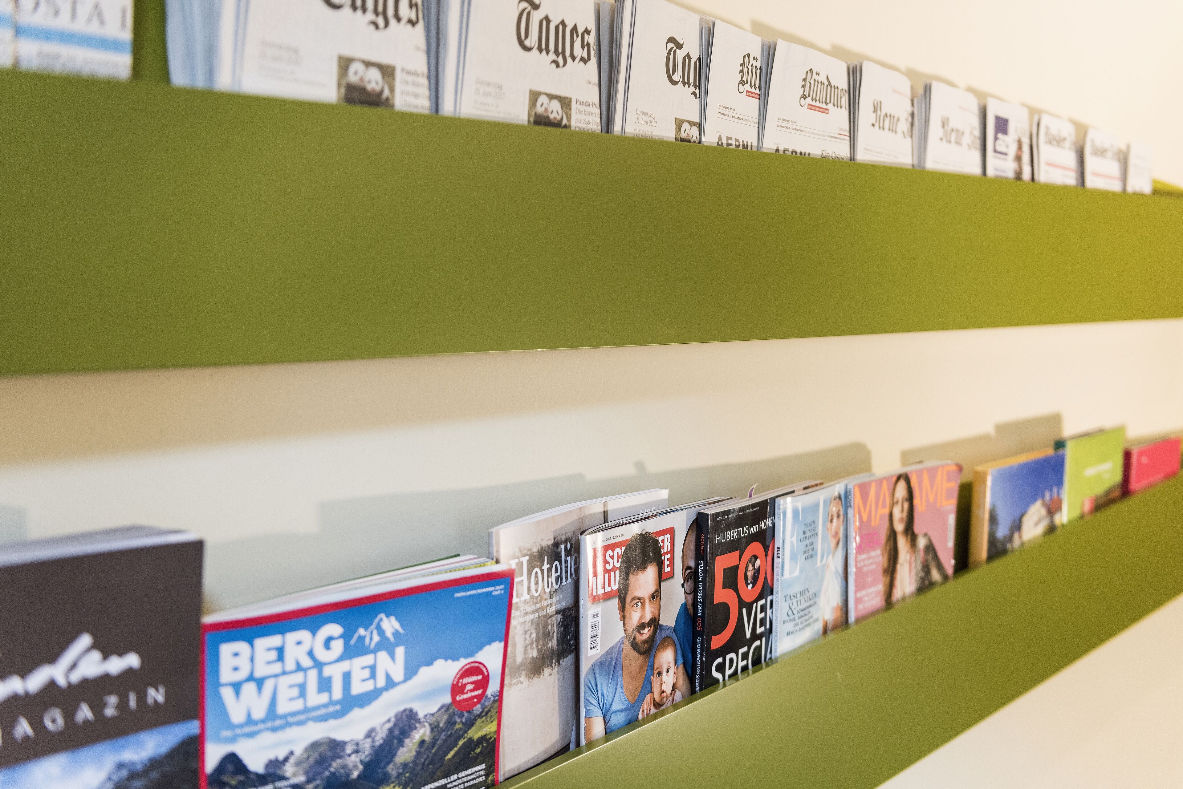 Una hilera de revistas en un estante, incluyendo títulos como 'BERG WELTEN' y 'Hotelit'.