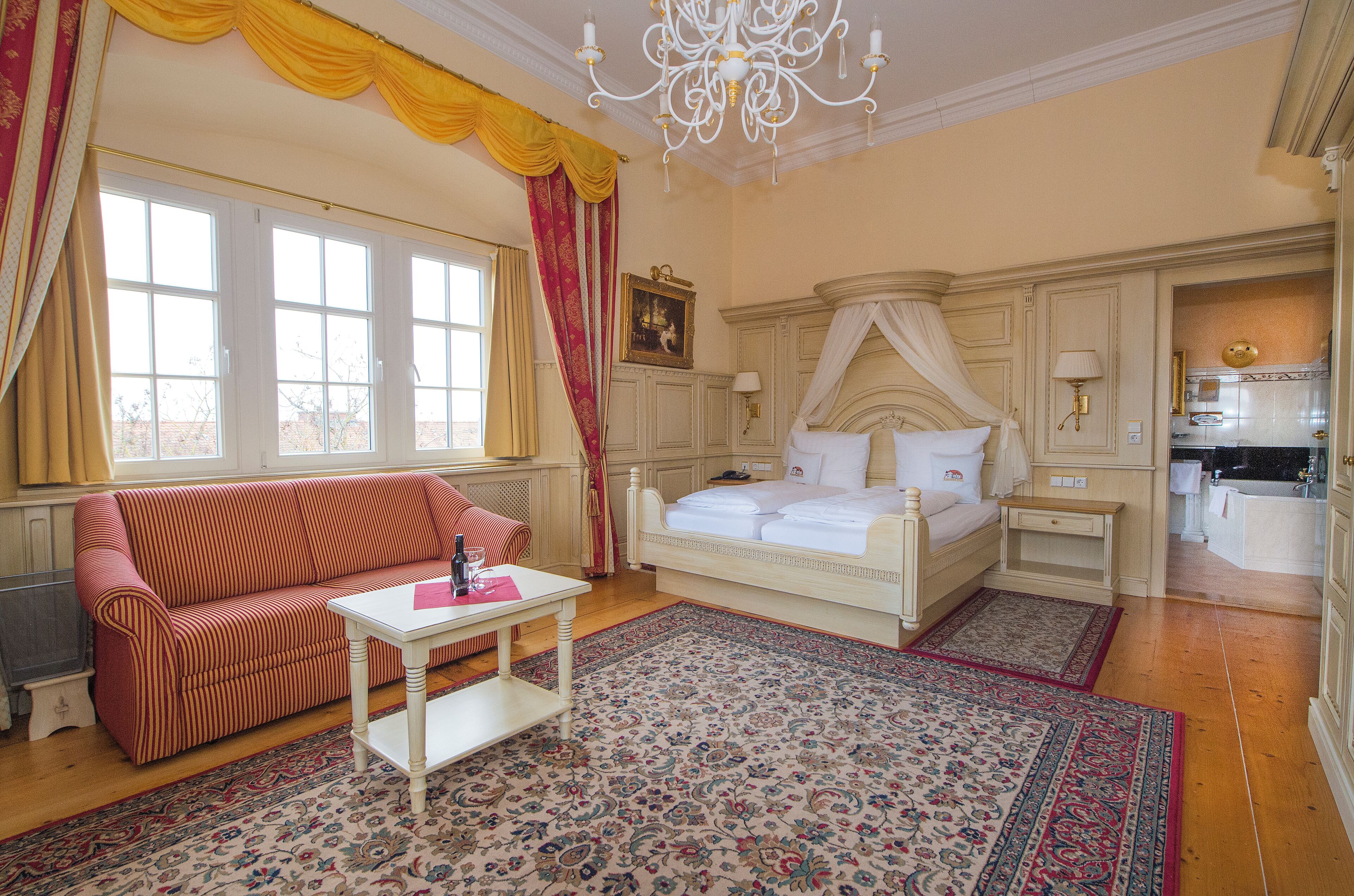 Une chambre à coucher avec un lit, un canapé, une table et une grande fenêtre.