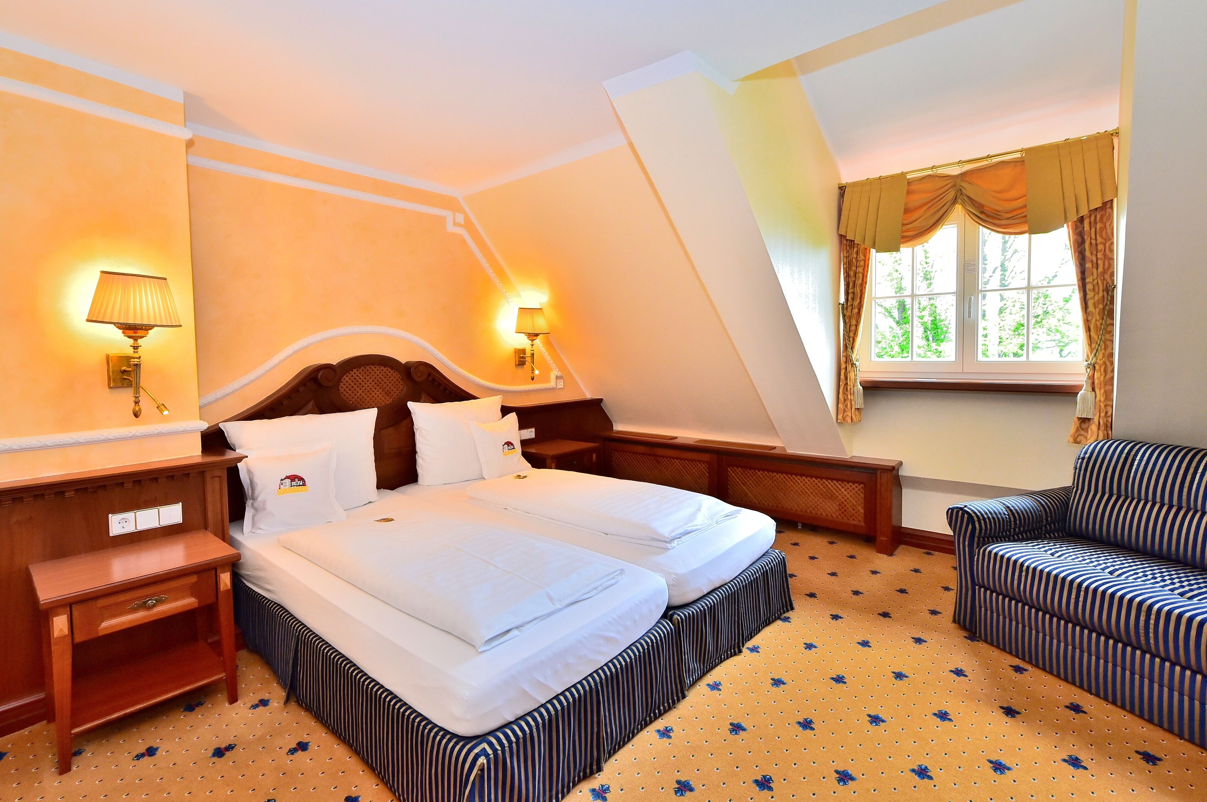A bedroom with a bed, bedside tables, a chair, and a window with curtains.