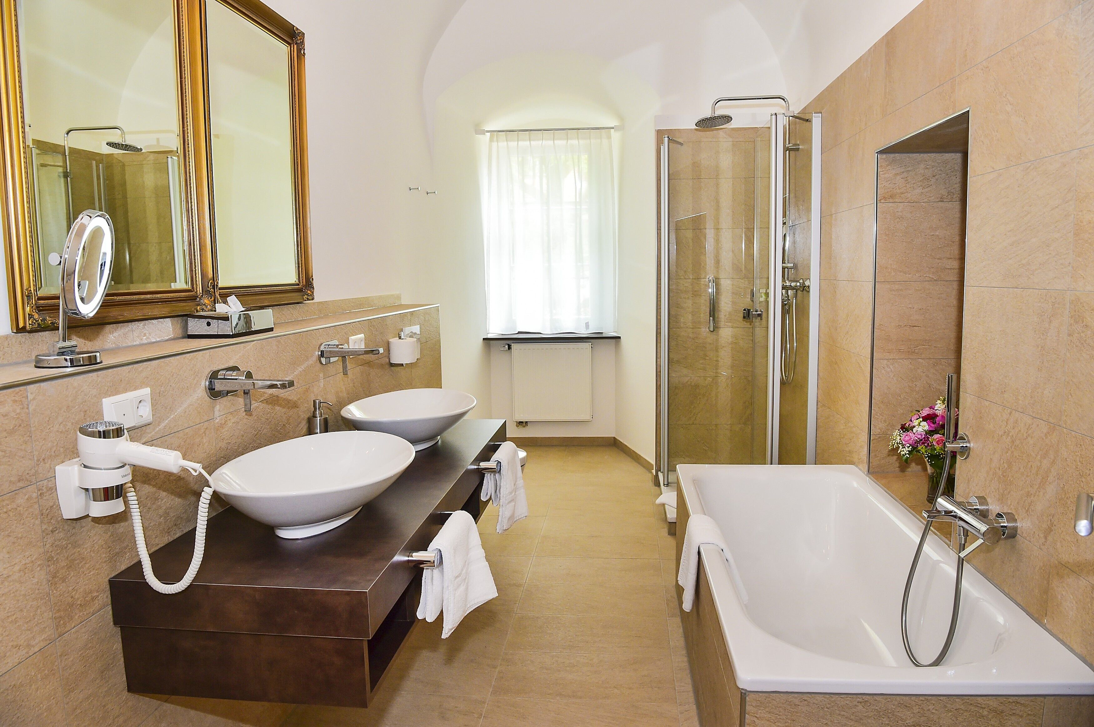 Un baño moderno con dos lavamanos, un espejo grande, una ducha y una bañera.