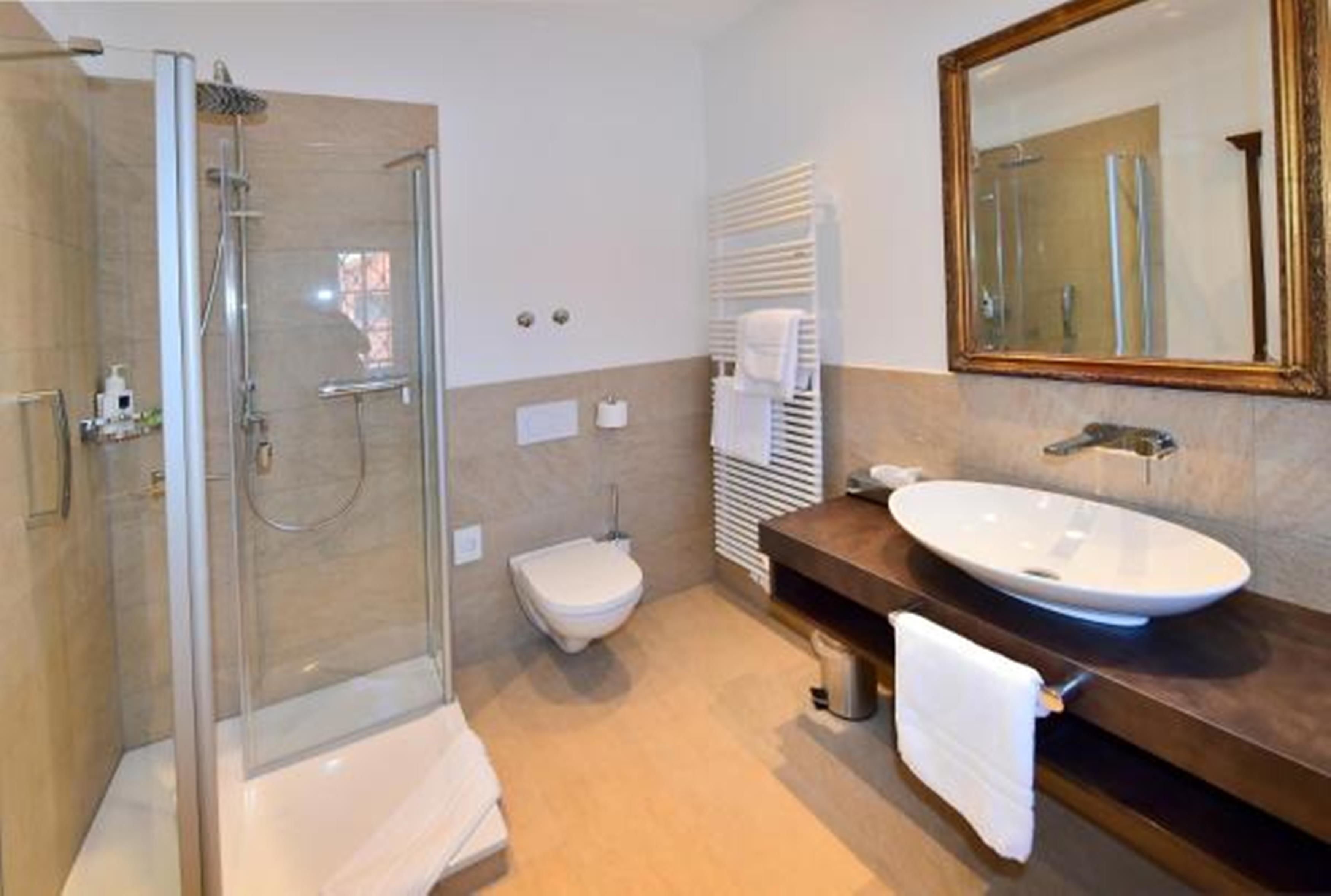 A modern bathroom with a glass-enclosed shower, a white toilet, a vanity with a sink, and a mirror.
