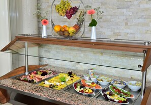 Un bufé con diferentes opciones de comida y una cesta de frutas sobre una barra.