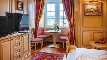Ein Hotelzimmer mit Bett, Schreibtisch mit Stuhl, Fernseher und einem Fenster mit Vorhängen.