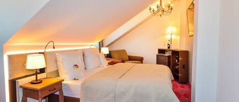 A hotel room with a bed, bedside table, lamp, and a nightstand.