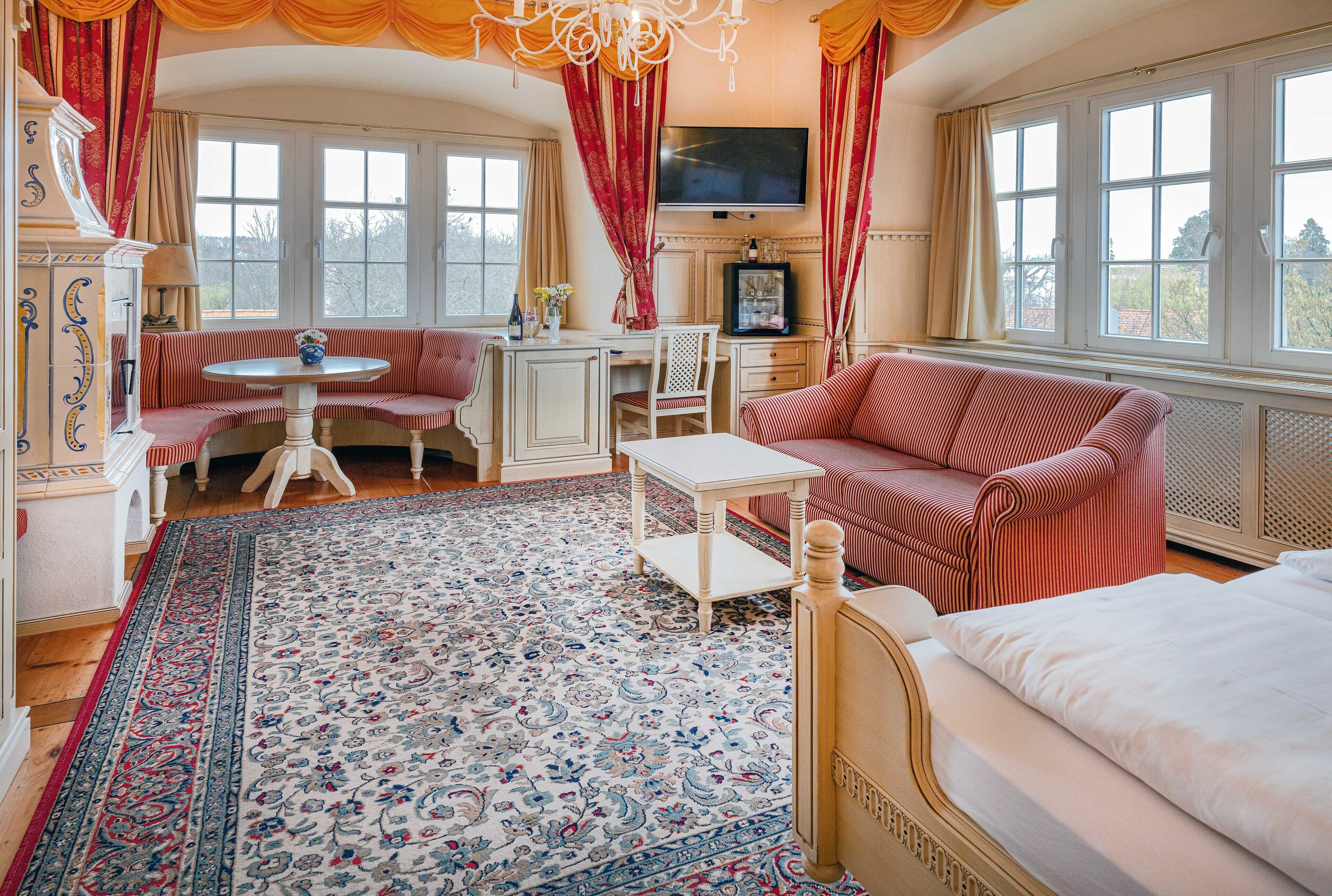 A room with a bed, a sofa, a desk, and a television.