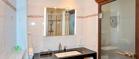 A modern bathroom with a black countertop sink, a mirror, and a glass shower enclosure.