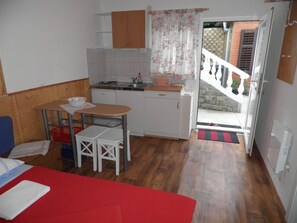 Une cuisine compacte avec un coin repas, une petite table et un canapé rouge.