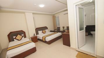 Two single beds with wooden headboards and matching nightstands, white linens, and a small table.