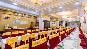 A banquet hall with rows of tables set for a formal event, a reception desk, and a chandelier. - Hai Long Hotel (Hai Phong)