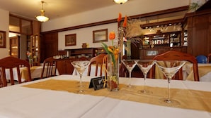 Un restaurante con una mesa dispuesta para cuatro, con un jarrón de flores y un cartel de menú.