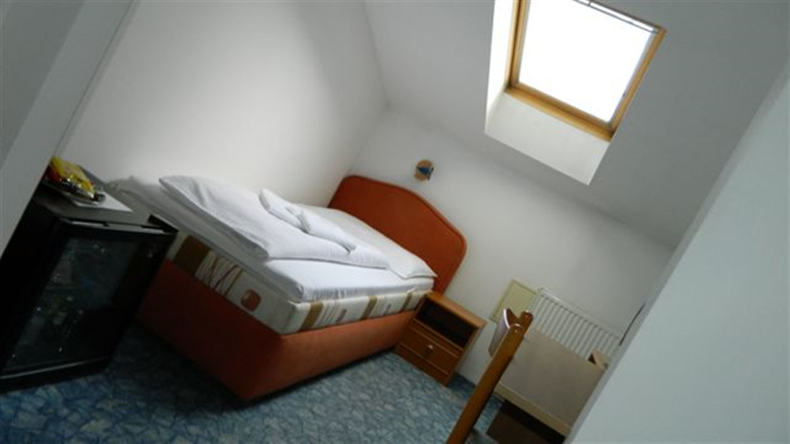 A small, compact room with a single bed, a desk, and a radiator.