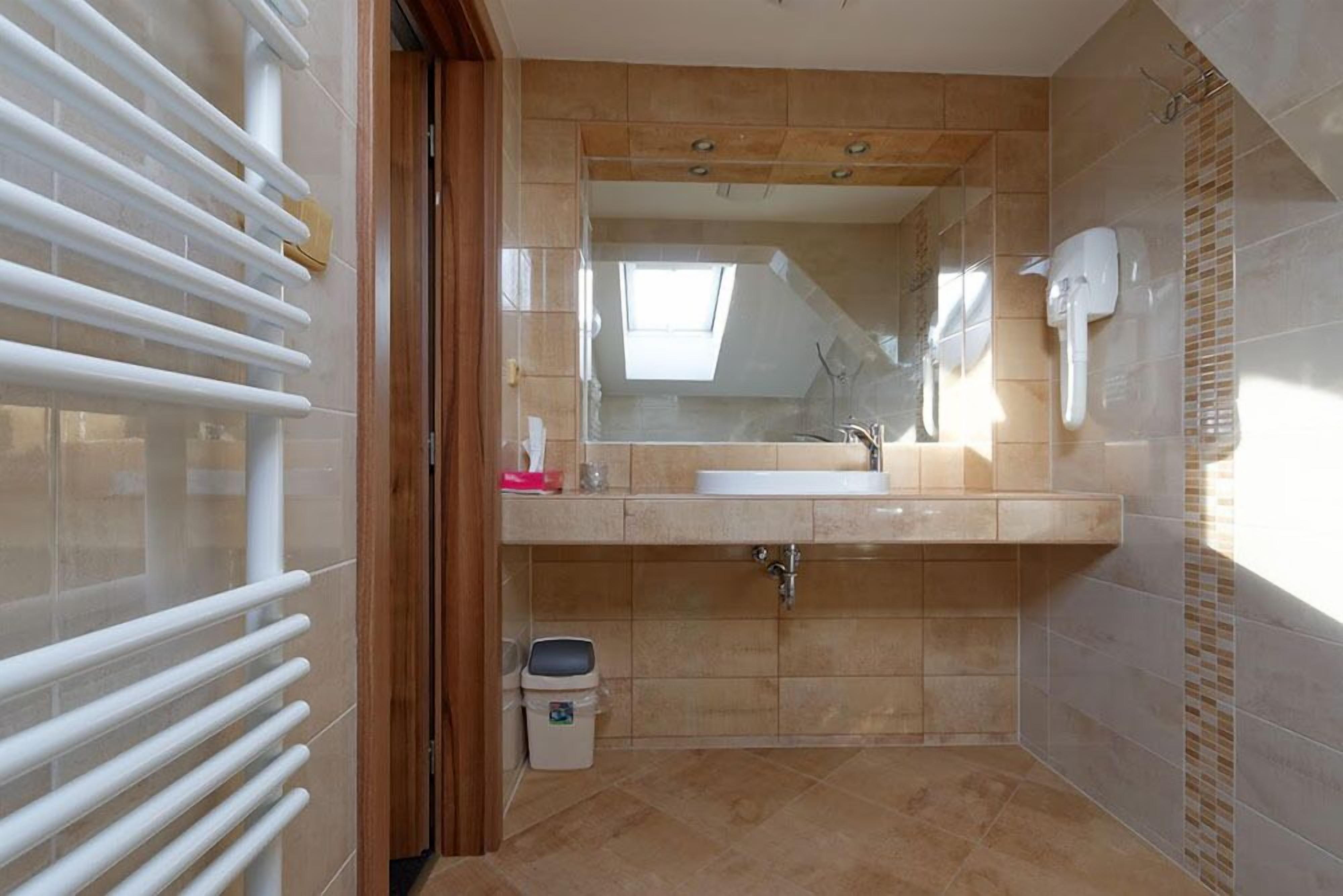Un baño con un espejo grande, un lavamanos y una zona de ducha.