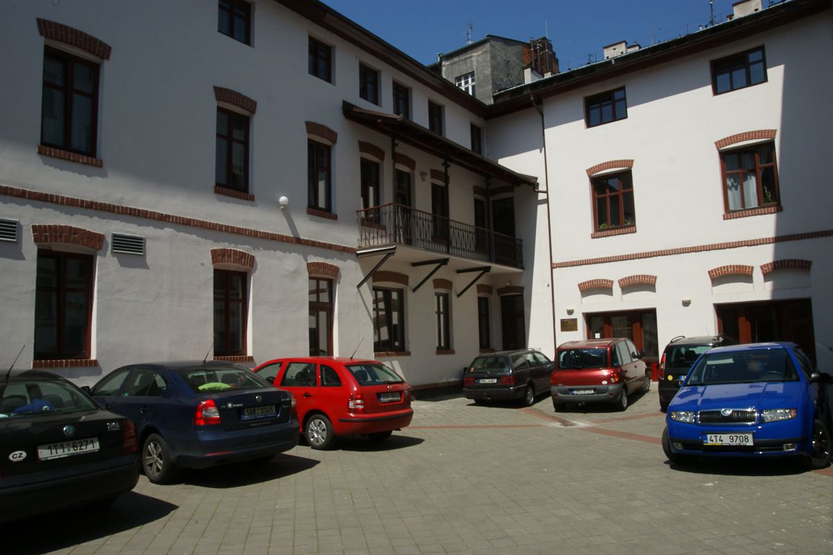 Un’area di parcheggio con diverse auto parcheggiate di fronte a un edificio bianco con molte finestre e balconi.