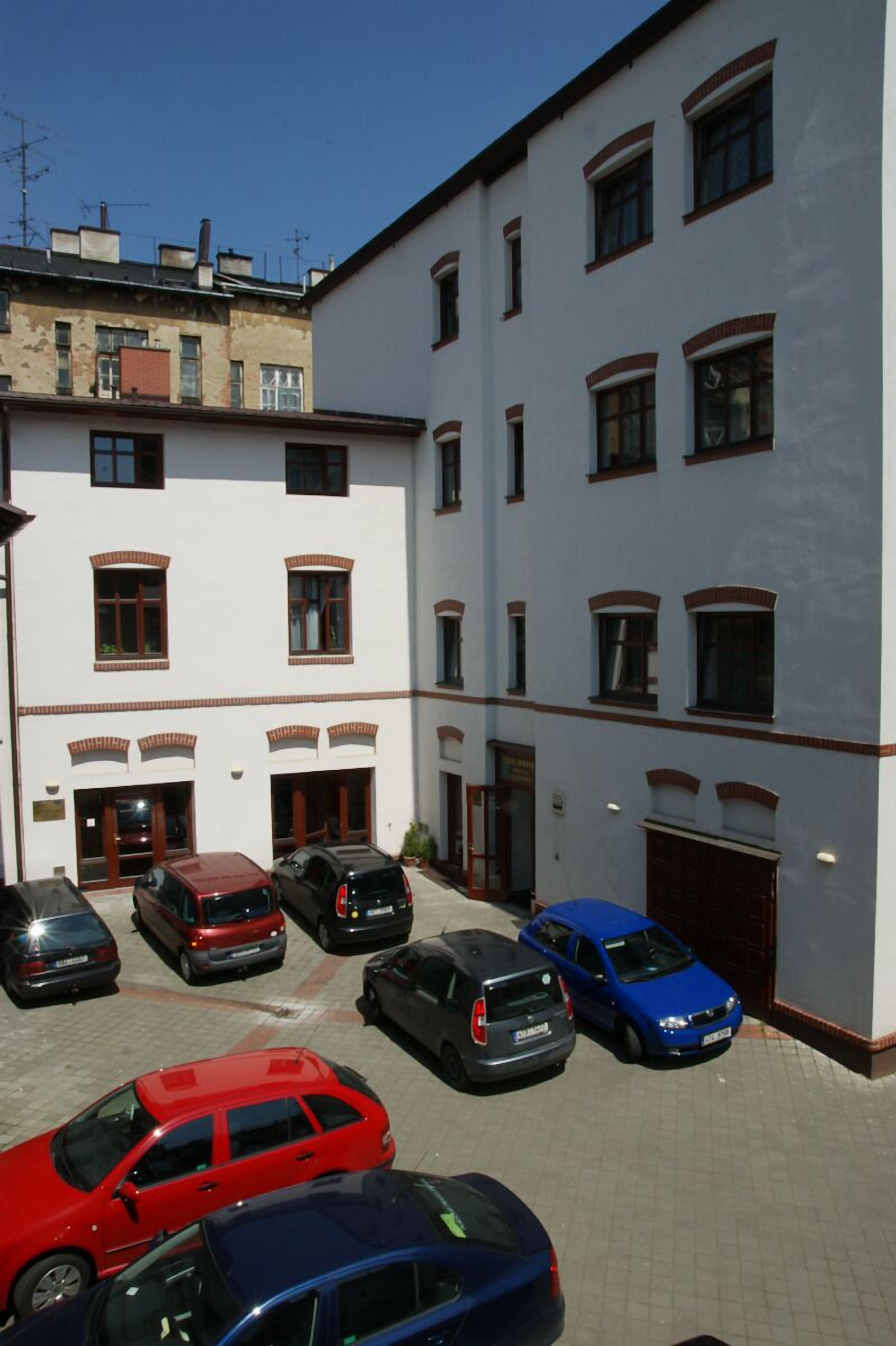 A multi-story building with several parked cars in front.
