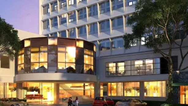 Un hotel moderno con varios pisos, ventanas amplias y un área de entrada bien iluminada.