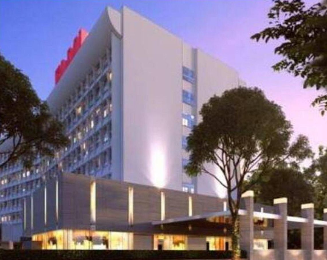 A multi-story hotel with a modern design, featuring a prominent red accent on the top of the building.
