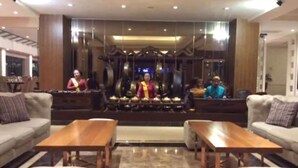 Un lobby moderno con sofás, una mesa de centro de madera y una pared decorativa con adornos colgantes.