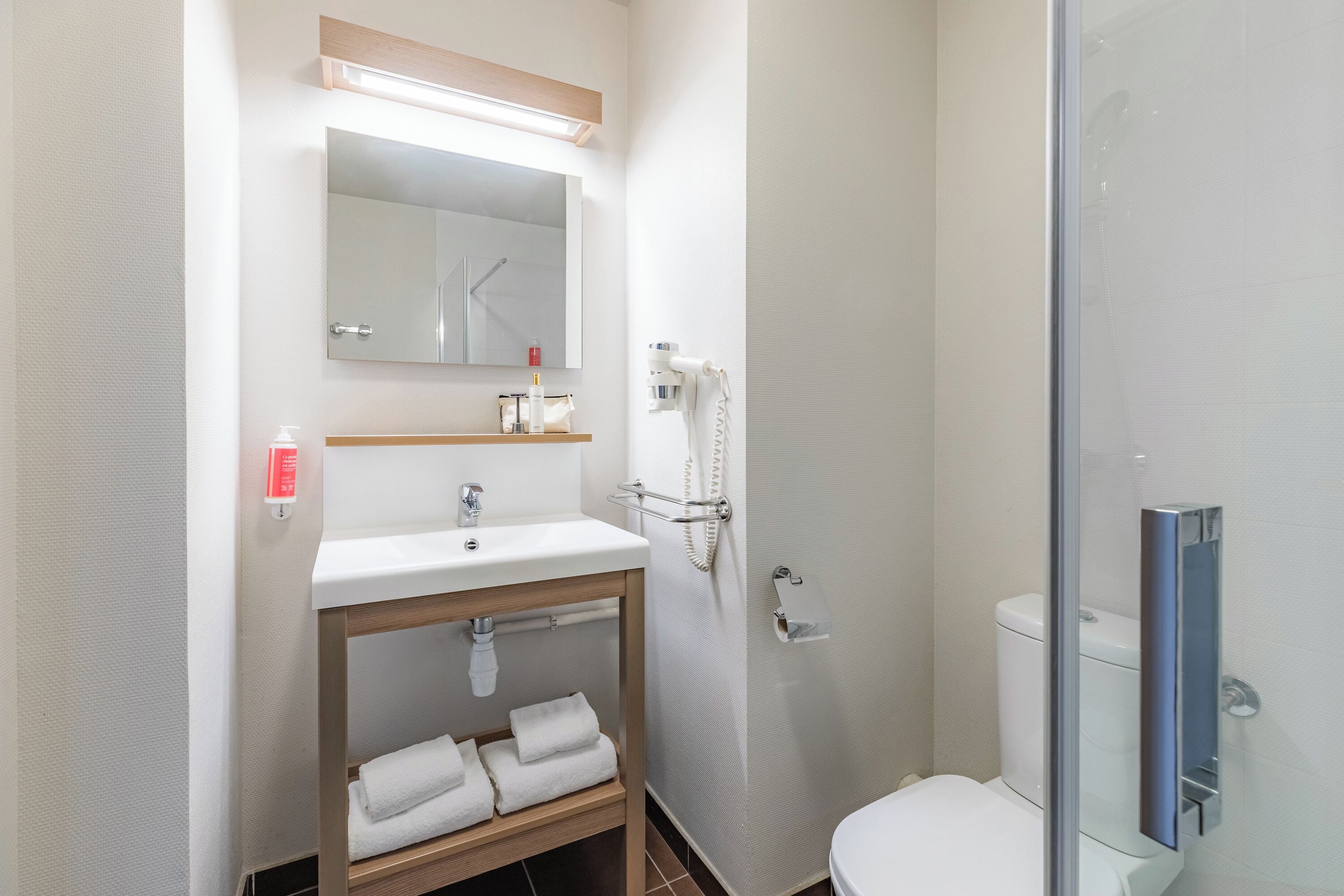 Een moderne badkamer met een wastafel, spiegel, handdoekhouder en toilet.