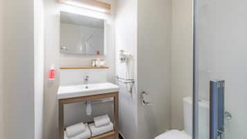 A modern bathroom with a sink, mirror, towel rack, and toilet.