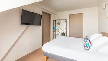 Une chambre d’hôtel avec un lit, un téléviseur fixé au mur et une armoire.