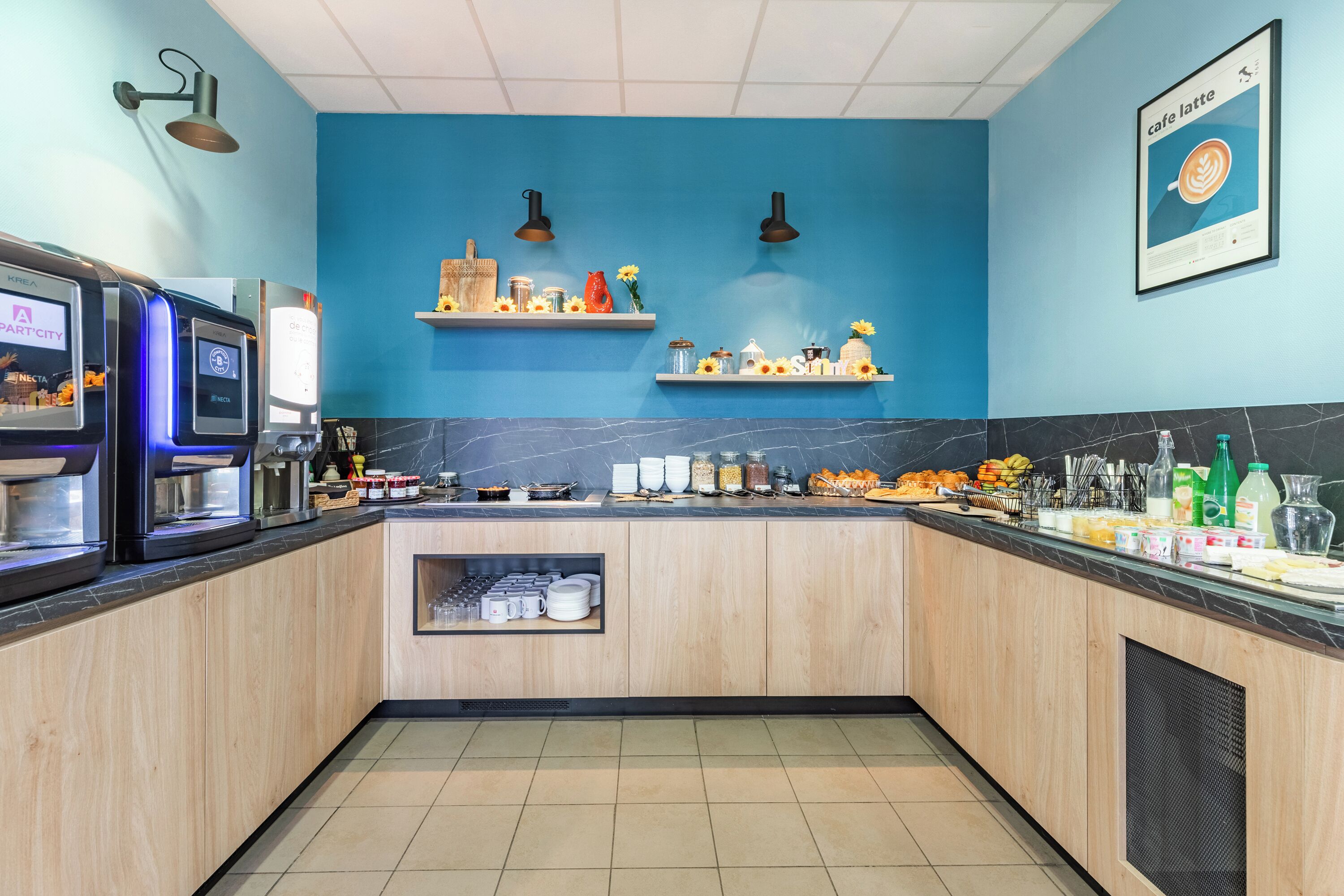 A modern kitchen with wooden cabinets, a marble countertop, and a blue accent wall.