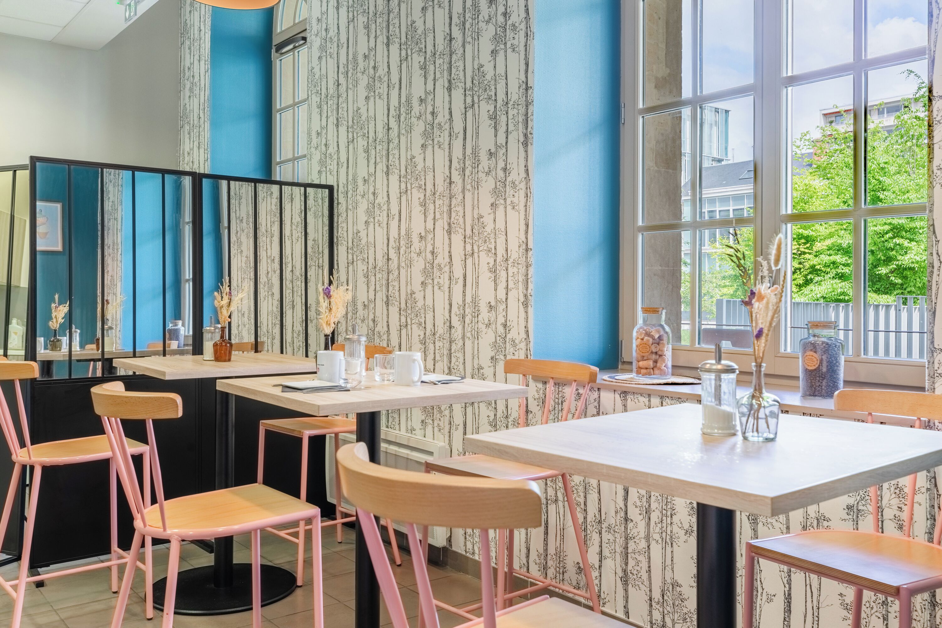 A restaurant with a modern interior, featuring striped wallpaper, large windows, and wooden chairs.