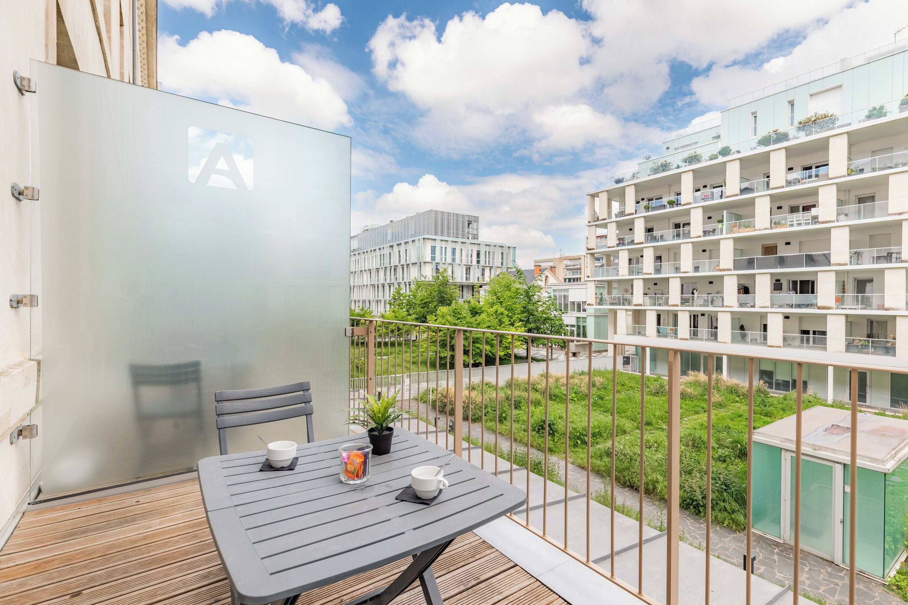 A balcony with a table, chairs, and a potted plant.