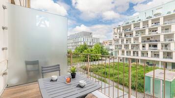 A balcony with a table, chairs, and a potted plant.