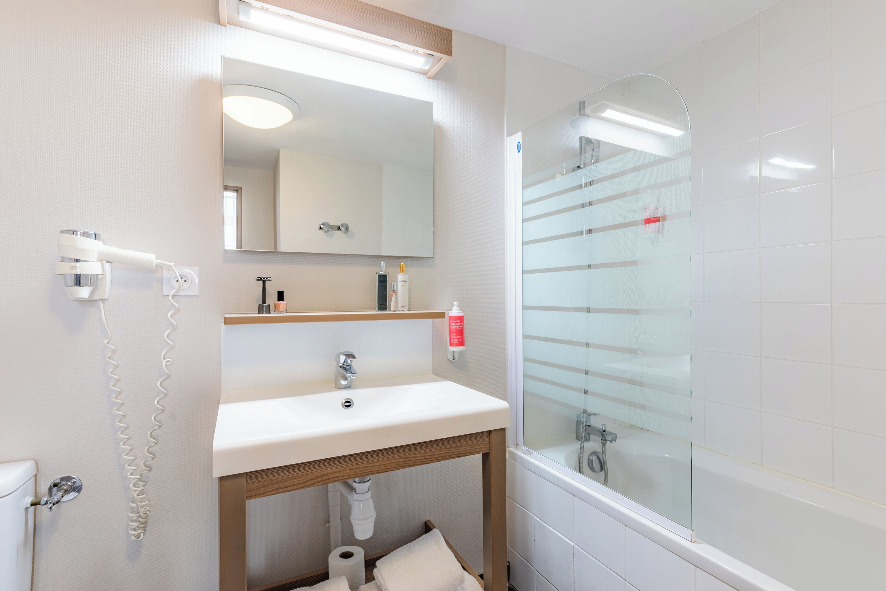Un bagno moderno con lavandino bianco, specchio e cabina doccia in vetro.