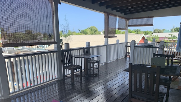 Una terraza techada al aire libre con mobiliario de madera, una colchoneta de yoga y mancuernas.