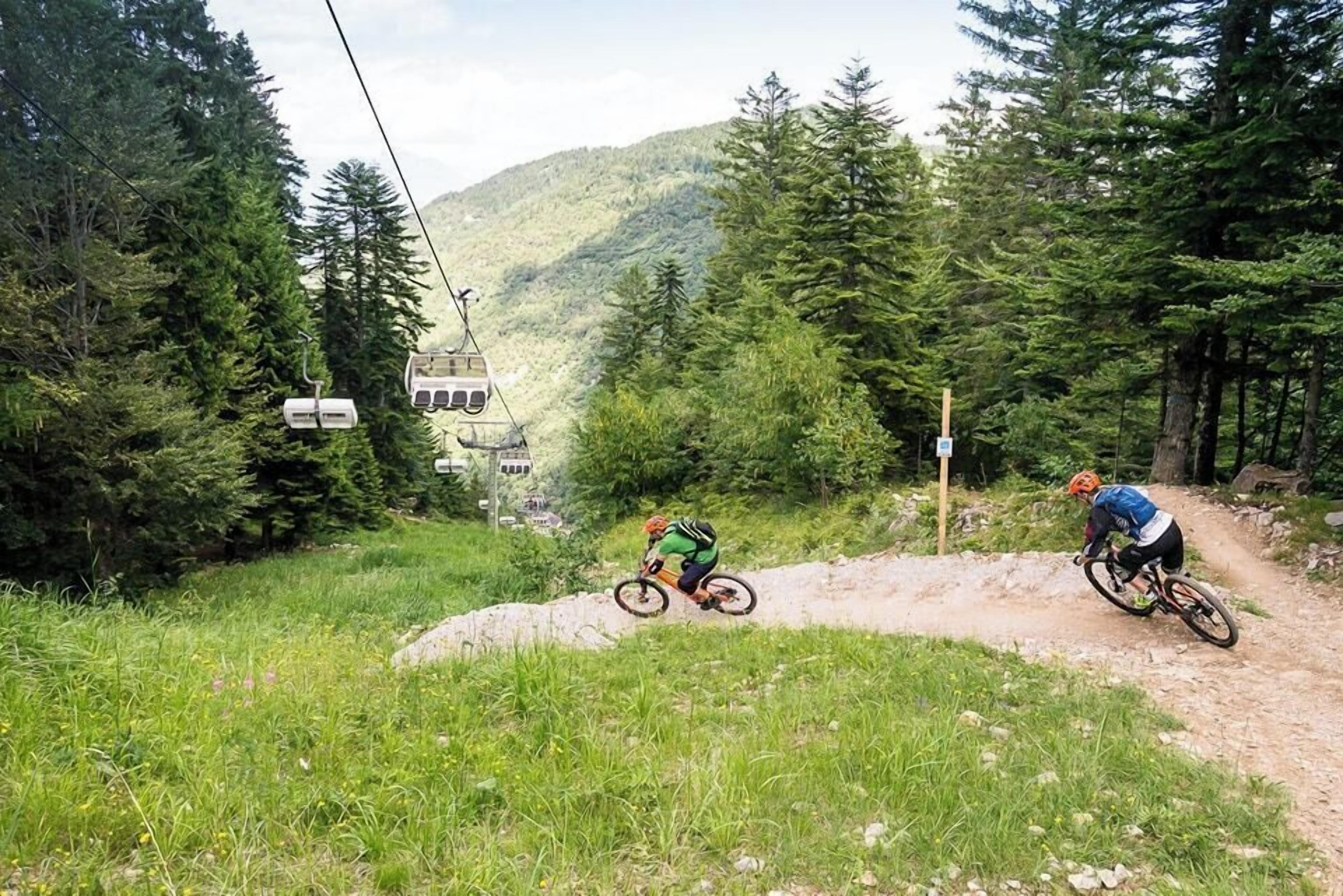 A mountain biking trail with a cable car in the background.