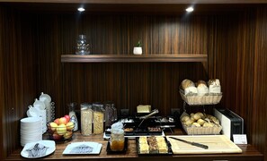 A breakfast buffet setup with various food items, utensils, and a cutting board. - DeSilva Premium Opole (Opole)