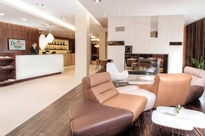 A modern hotel lobby with leather sofas, a reception desk, and a bar area. - DeSilva Premium Opole (Opole)