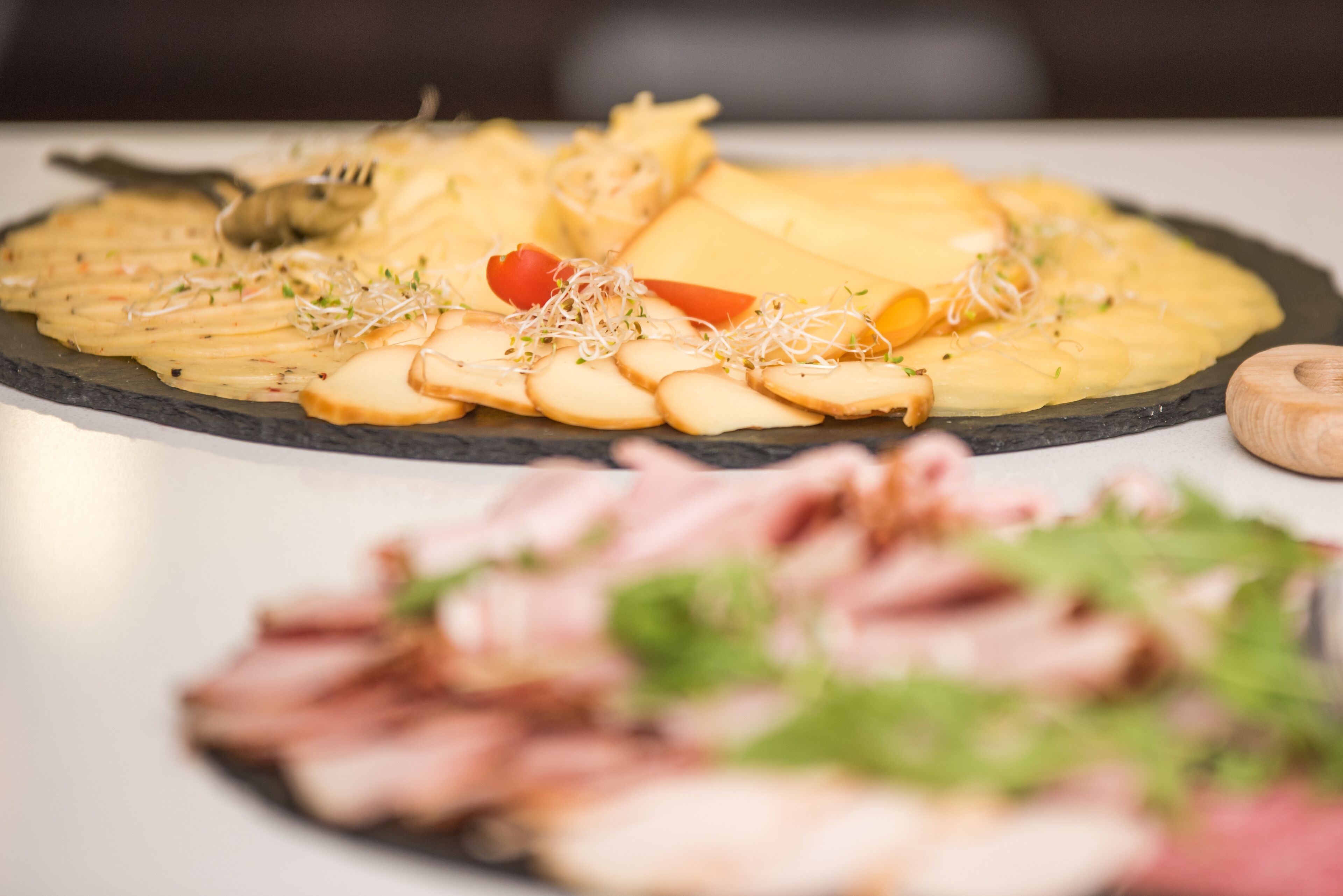 A variety of food items on a slate serving board, including sliced meats, cheese, and garnishes.