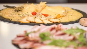 A variety of food items on a slate serving board, including sliced meats, cheese, and garnishes.