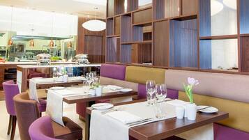 A restaurant with multiple dining tables, purple and brown upholstered booths, and a modern wooden panel wall design.