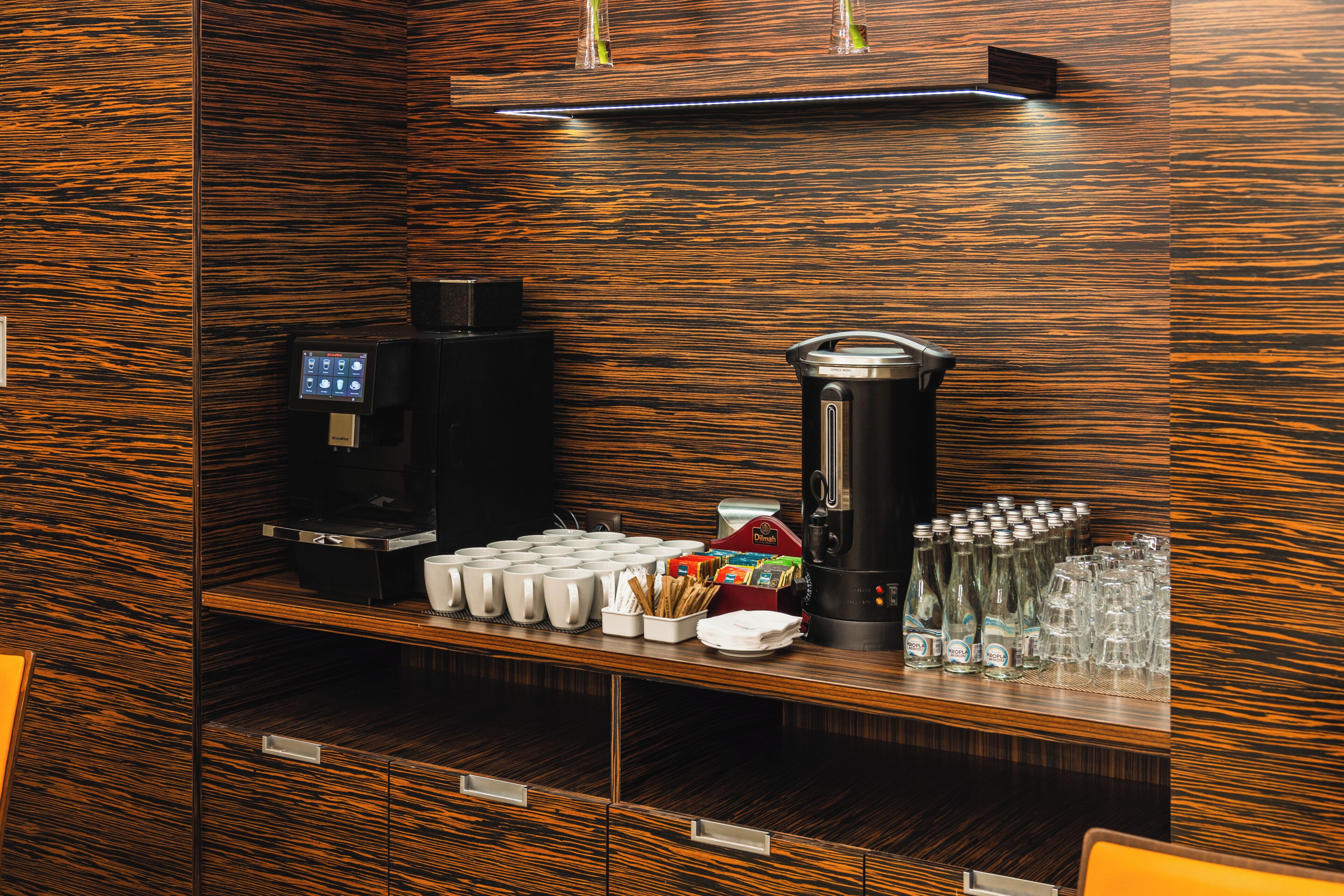 Una estación de café con cafetera, tazas y dispensador de agua.