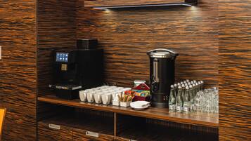 Una estación de café con cafetera, tazas y dispensador de agua.