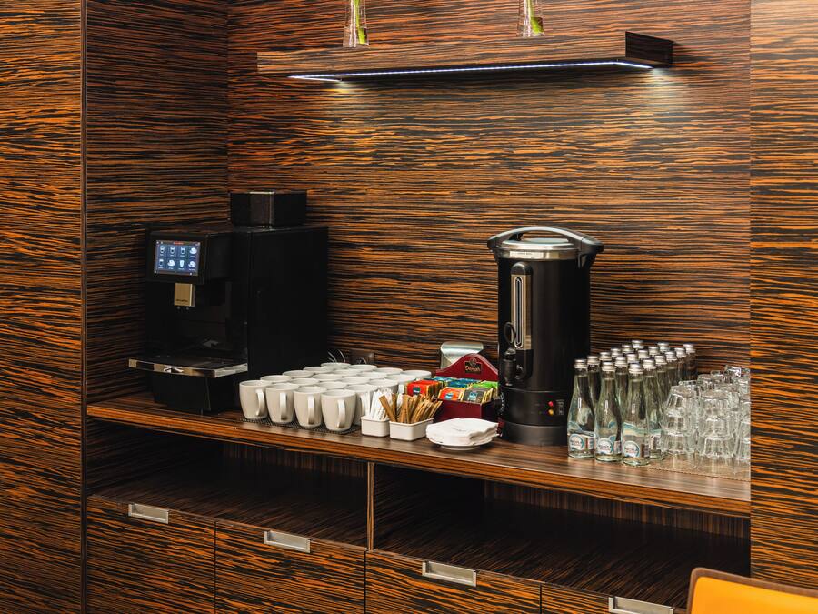 Una estación de café con cafetera, tazas y dispensador de agua.
