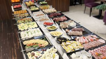 A buffet spread with various food items including fruits, cheeses, and meats.