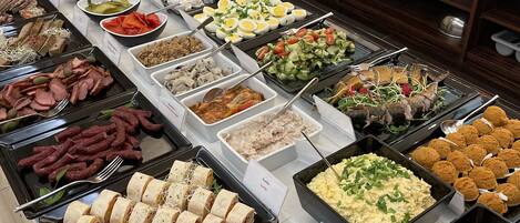 Un buffet proposant une variété de plats, notamment des viandes, des salades et des desserts.