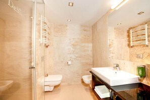 A modern bathroom with a glass shower enclosure, a white sink, and a bidet. - DeSilva Premium Opole (Opole)