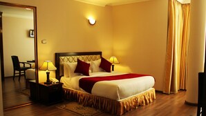 Une chambre d’hôtel avec un grand lit, deux lampes de chevet, une table de chevet avec un téléphone, un miroir et une chaise.