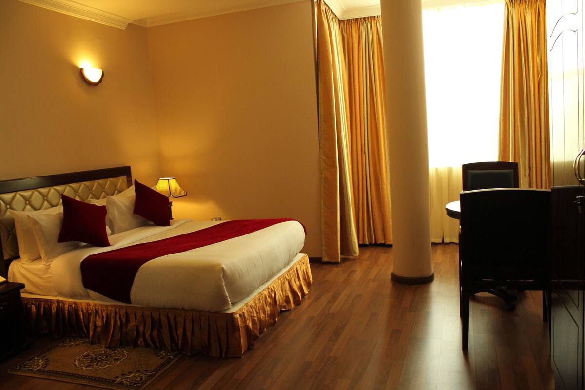 A hotel room with a large bed, a desk, and a chair.
