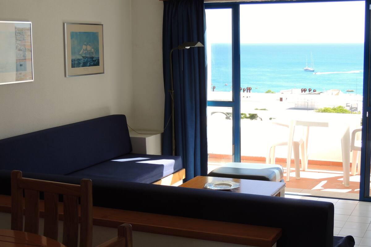 Una habitación con sofá, una mesa de comedor y vista al mar.